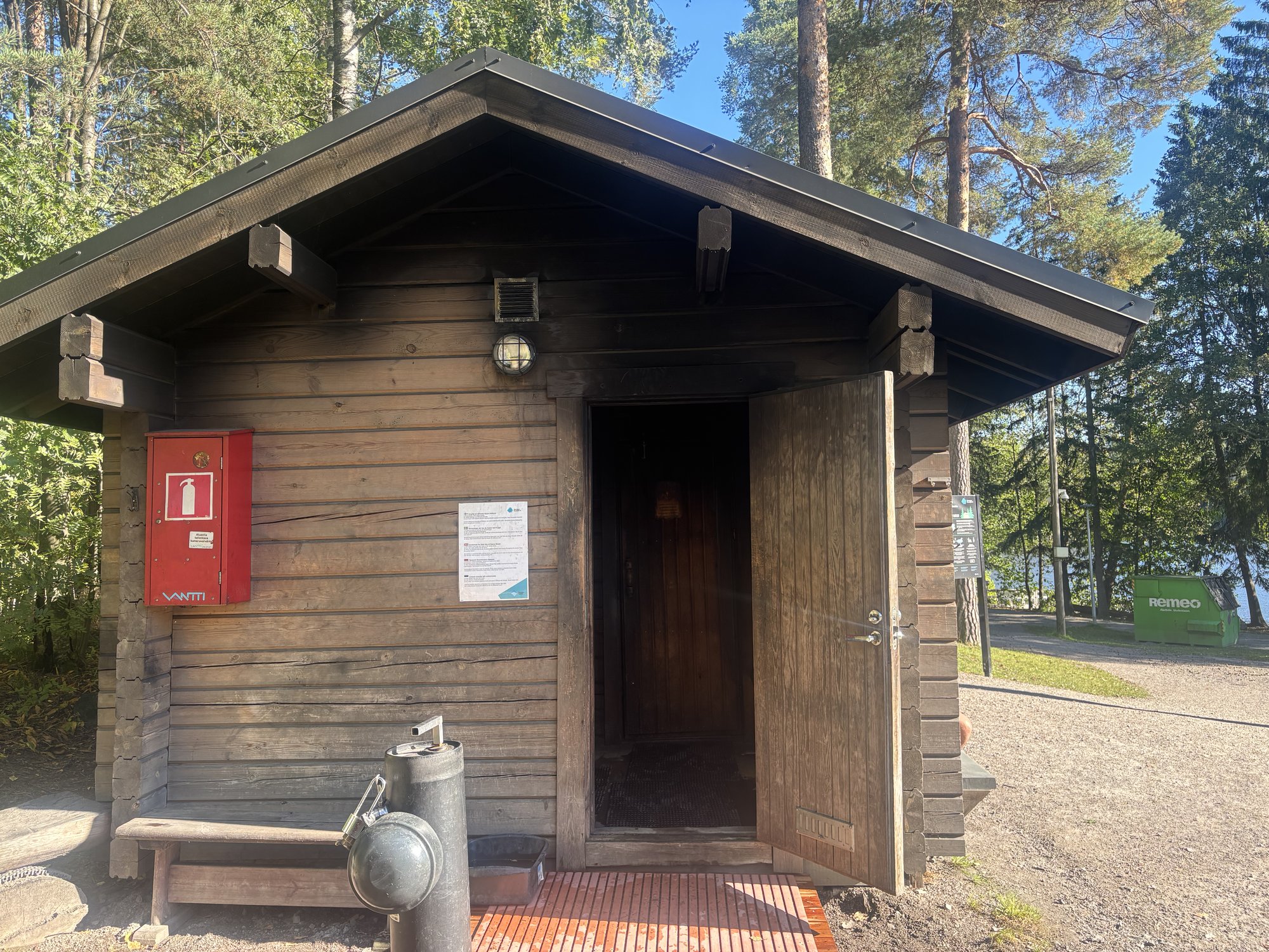 木造の小さなサウナ小屋の正面、ドアが開いている様子